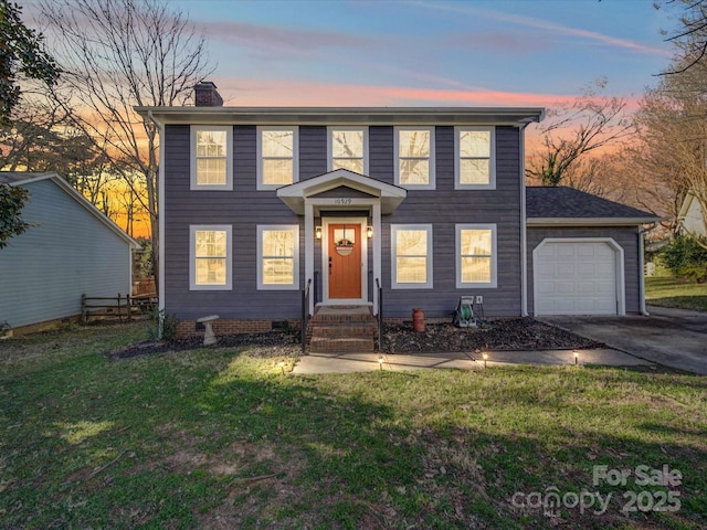 colonial-style house with a garage, concrete driveway, a chimney, crawl space, and a front yard