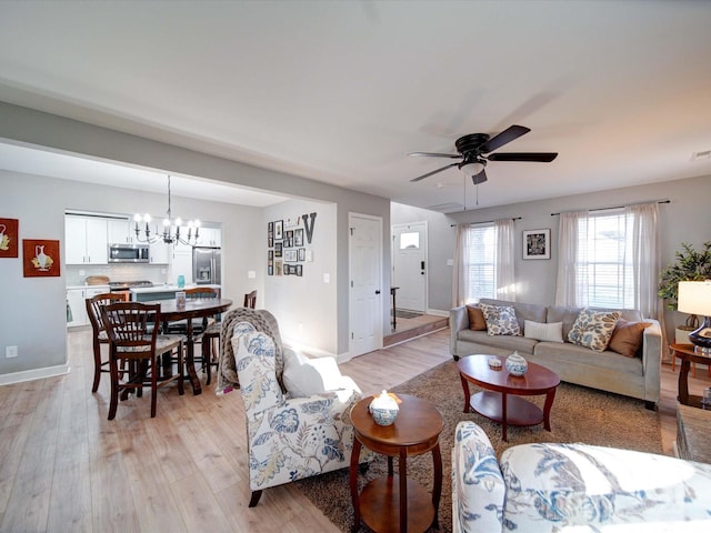 living room with ceiling fan with notable chandelier, light wood finished floors, and baseboards