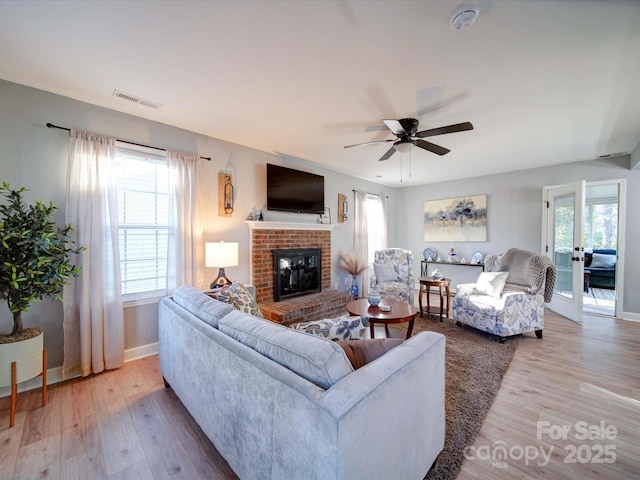 living area with light wood-type flooring, visible vents, and a wealth of natural light