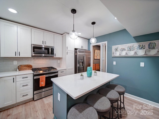 kitchen with stainless steel appliances, white cabinets, decorative backsplash, and a kitchen bar