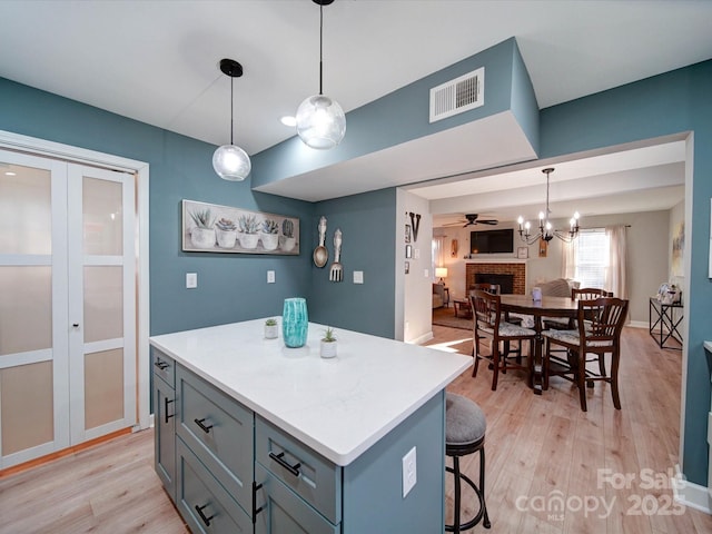 kitchen featuring light wood-style floors, a fireplace, visible vents, and a center island