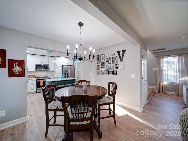 dining room with light wood-type flooring, visible vents, a notable chandelier, and baseboards