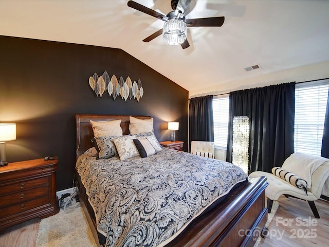 bedroom with ceiling fan, multiple windows, visible vents, and vaulted ceiling