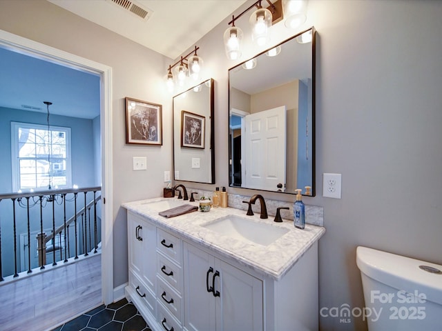 full bath featuring double vanity, a sink, visible vents, and an inviting chandelier