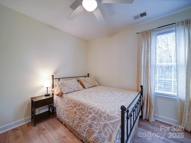 bedroom with light wood finished floors, multiple windows, visible vents, and baseboards