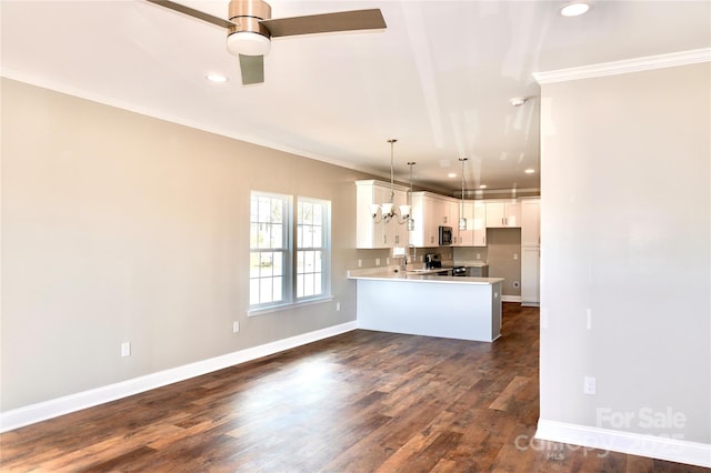 kitchen featuring ornamental molding, white cabinets, a peninsula, and dark wood-style floors