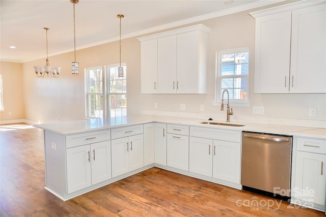 kitchen with light wood finished floors, dishwasher, a peninsula, crown molding, and a sink