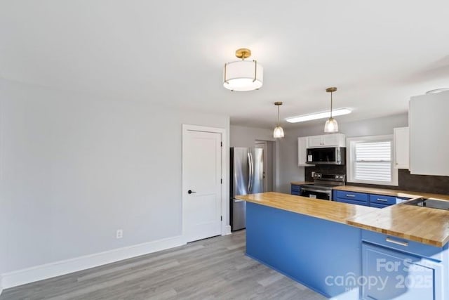 kitchen featuring light wood-type flooring, a peninsula, wooden counters, stainless steel appliances, and blue cabinets