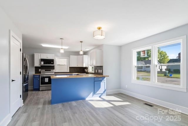 kitchen featuring baseboards, a peninsula, white cabinets, light wood-style floors, and stainless steel appliances