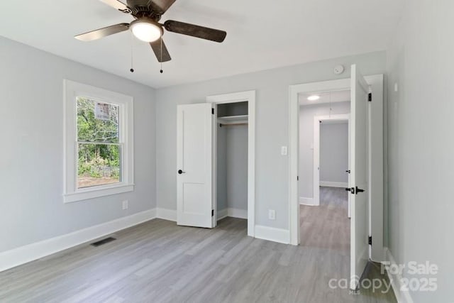 unfurnished bedroom featuring a closet, baseboards, visible vents, ceiling fan, and wood finished floors