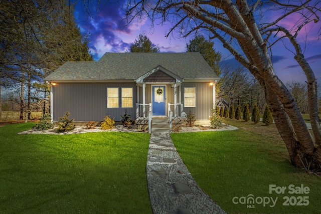 view of front facade featuring a front lawn and a shingled roof