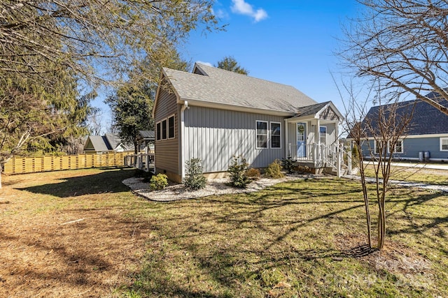 view of front facade featuring a front lawn, fence, roof with shingles, and crawl space