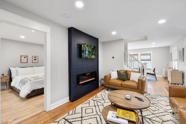 living room featuring stairway, baseboards, light wood-style flooring, recessed lighting, and a fireplace