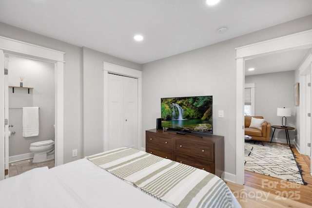 bedroom with baseboards, light wood finished floors, ensuite bath, recessed lighting, and a closet