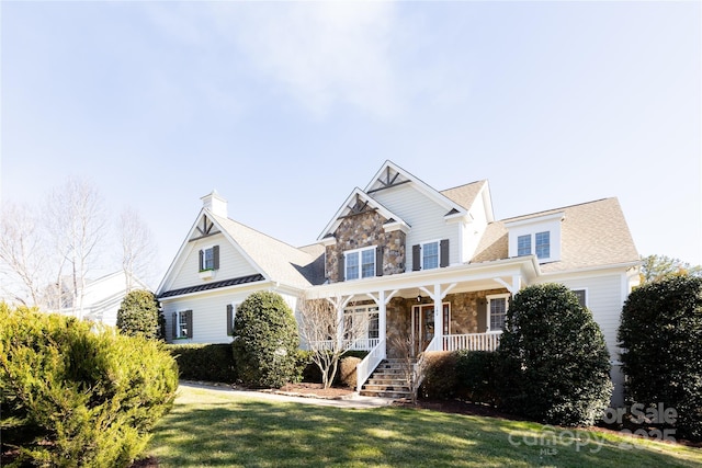 view of front of house featuring a porch, a front yard, and stone siding