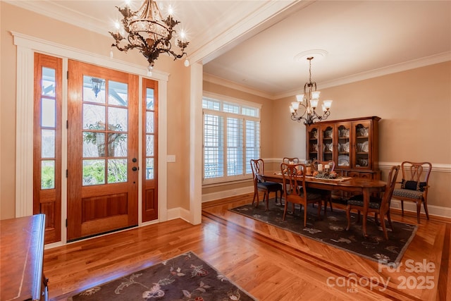 dining space featuring a chandelier, baseboards, wood finished floors, and crown molding