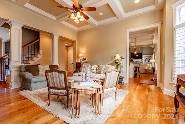 living area featuring decorative columns, coffered ceiling, stairway, light wood-type flooring, and beam ceiling