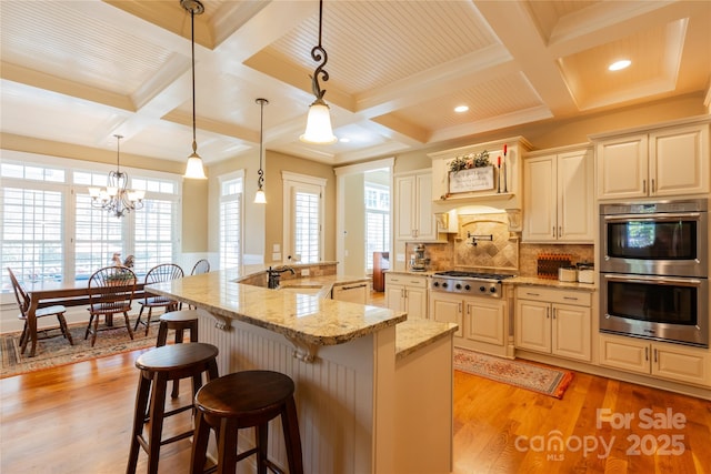 kitchen featuring tasteful backsplash, light wood-style flooring, a breakfast bar area, appliances with stainless steel finishes, and a sink