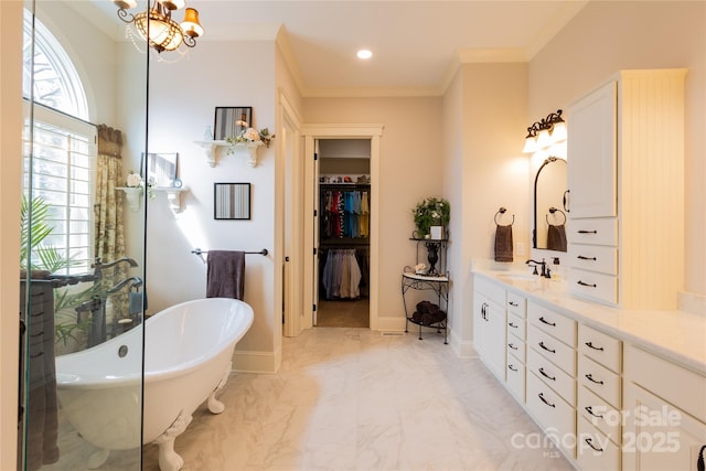 bathroom with baseboards, ornamental molding, marble finish floor, a freestanding bath, and vanity