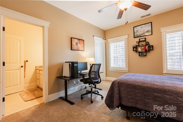 carpeted bedroom with a ceiling fan, connected bathroom, visible vents, and baseboards