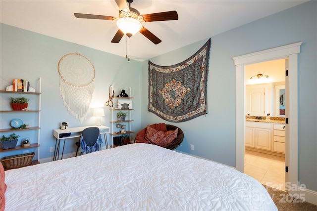 bedroom with light tile patterned floors, ensuite bath, and baseboards