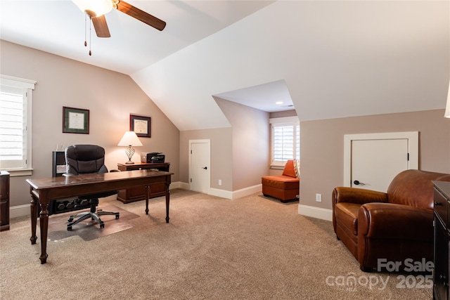 office area with vaulted ceiling, ceiling fan, baseboards, and light colored carpet