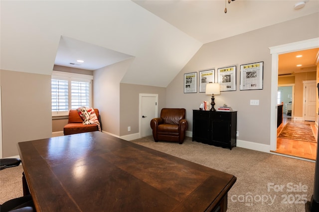 office space featuring lofted ceiling, baseboards, visible vents, and light colored carpet