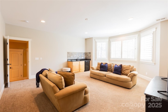 living room featuring visible vents, baseboards, light colored carpet, indoor wet bar, and recessed lighting