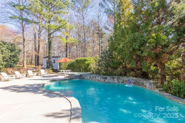 pool with a patio area, an in ground hot tub, and an outbuilding