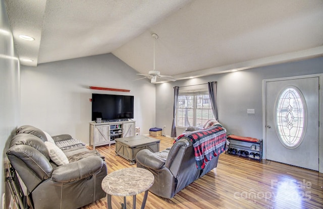 living area with lofted ceiling, light wood-style flooring, a textured ceiling, and a ceiling fan