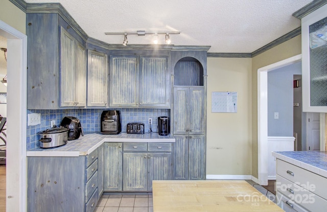 kitchen with a textured ceiling, ornamental molding, and tasteful backsplash