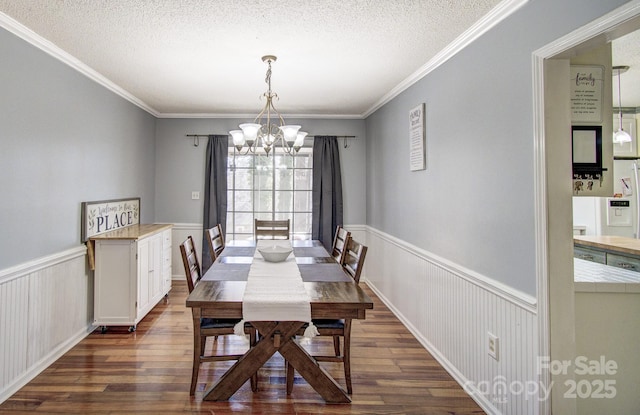 dining space with a textured ceiling, wainscoting, dark wood finished floors, and an inviting chandelier