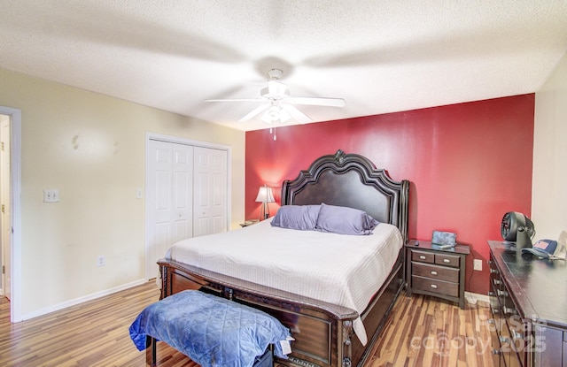 bedroom featuring a ceiling fan, a closet, light wood-style flooring, and baseboards