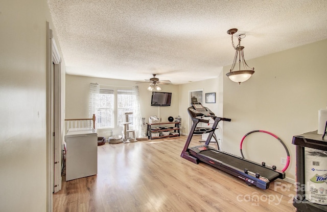 exercise room with a ceiling fan, a textured ceiling, and wood finished floors