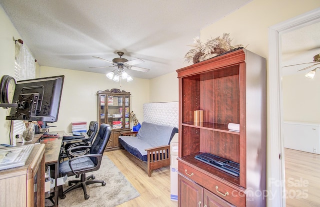 office space featuring a textured ceiling, light wood finished floors, and a ceiling fan