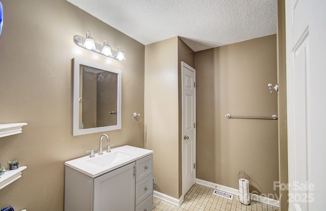 bathroom with a textured ceiling, vanity, baseboards, a closet, and tile patterned floors