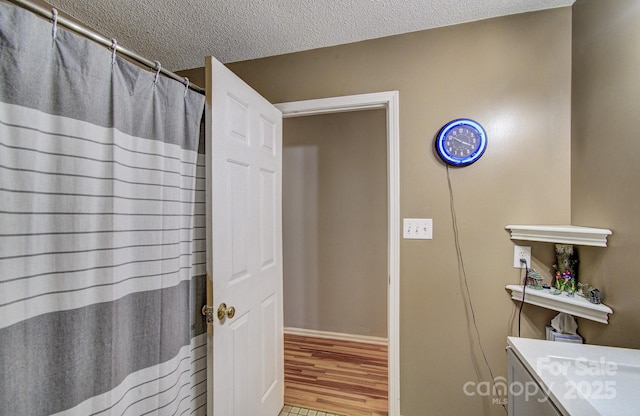 bathroom featuring a textured ceiling, baseboards, and wood finished floors