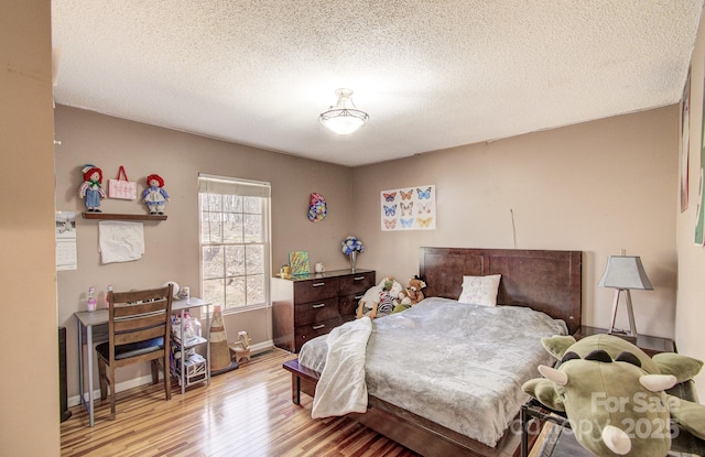 bedroom featuring light wood-type flooring, baseboards, and a textured ceiling