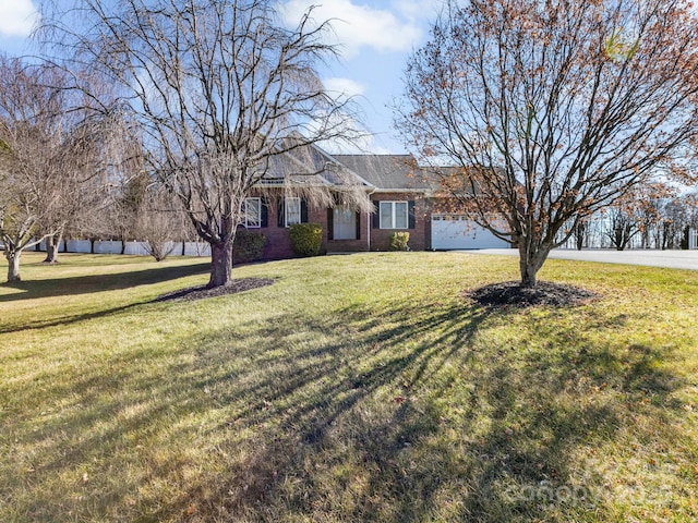 ranch-style home with driveway, brick siding, a front lawn, and an attached garage