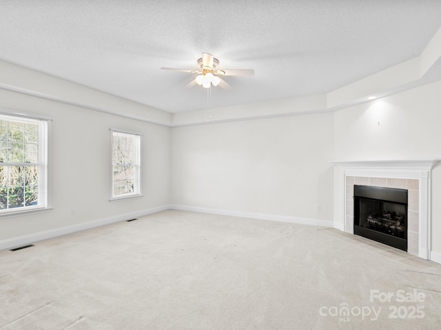 unfurnished living room featuring carpet, visible vents, baseboards, and a tile fireplace