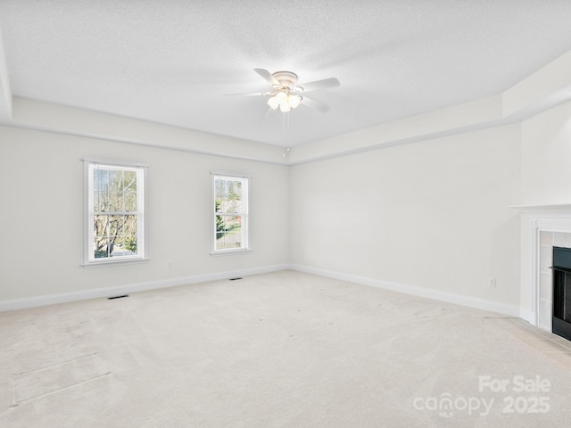 unfurnished living room with a fireplace, visible vents, light carpet, a textured ceiling, and baseboards