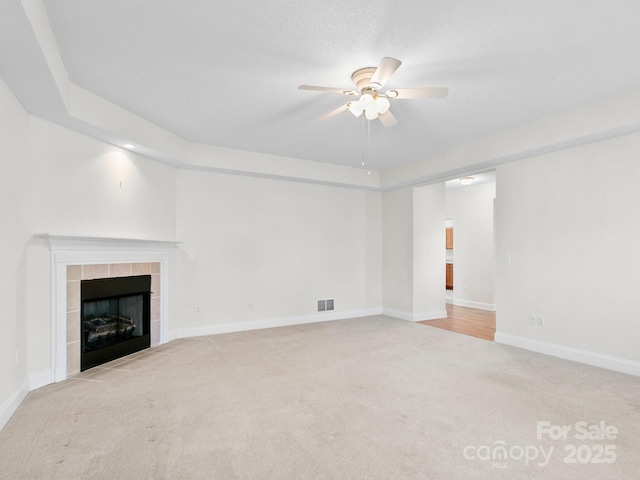 unfurnished living room featuring visible vents, baseboards, ceiling fan, carpet floors, and a fireplace