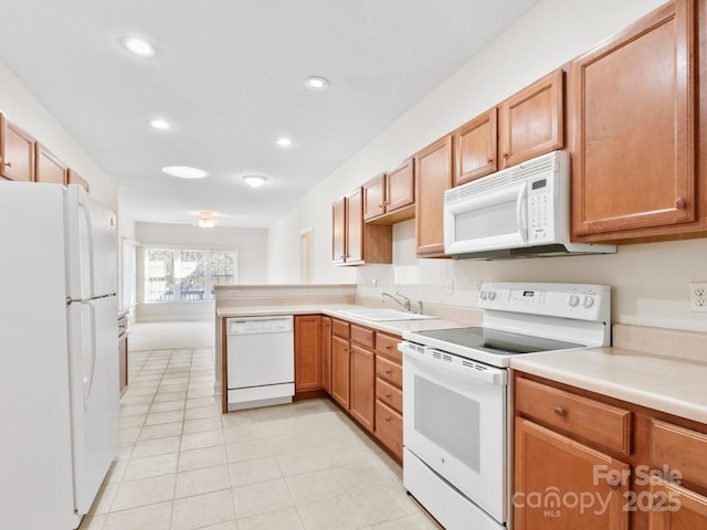 kitchen with recessed lighting, a peninsula, white appliances, a sink, and light countertops