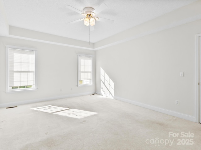 unfurnished room featuring a healthy amount of sunlight, carpet, visible vents, and baseboards