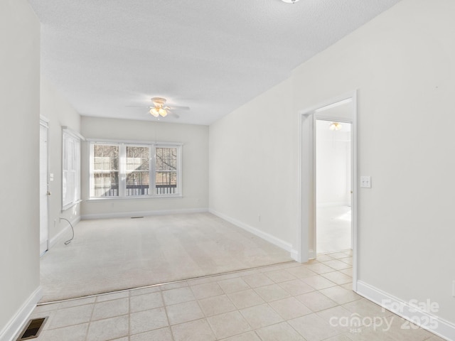 unfurnished room featuring baseboards, a textured ceiling, visible vents, and a ceiling fan