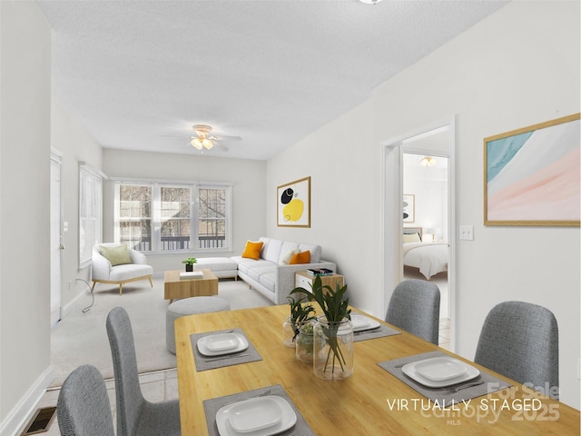 carpeted dining area featuring ceiling fan, a textured ceiling, visible vents, and baseboards