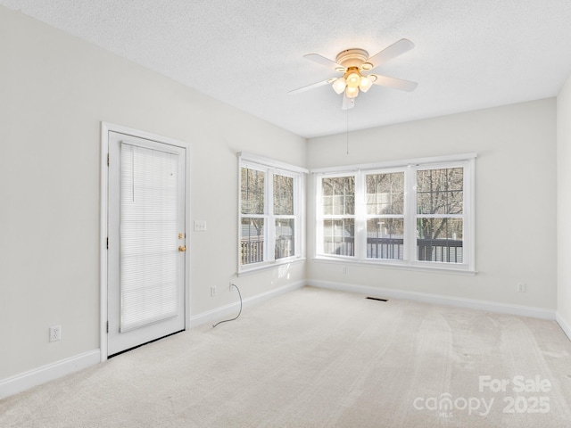 spare room with a textured ceiling, ceiling fan, carpet, and baseboards