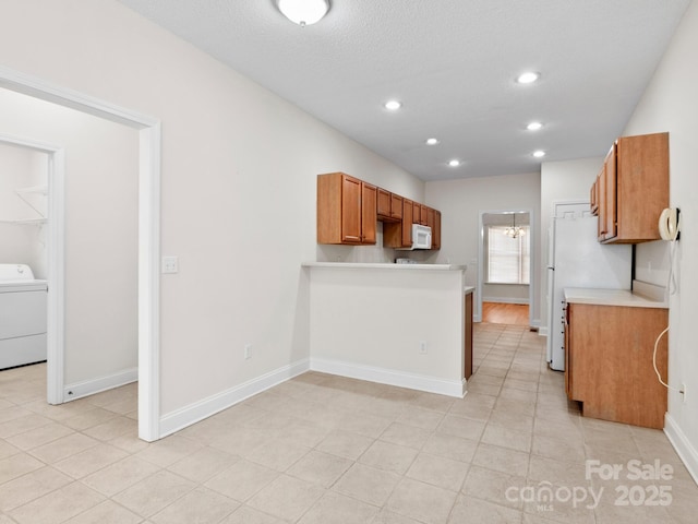 kitchen featuring recessed lighting, light countertops, brown cabinetry, washer / dryer, and white appliances