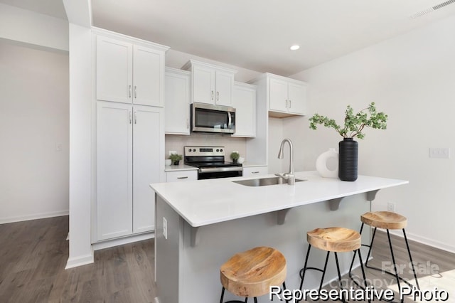 kitchen with a center island with sink, a breakfast bar, stainless steel appliances, light countertops, and a sink