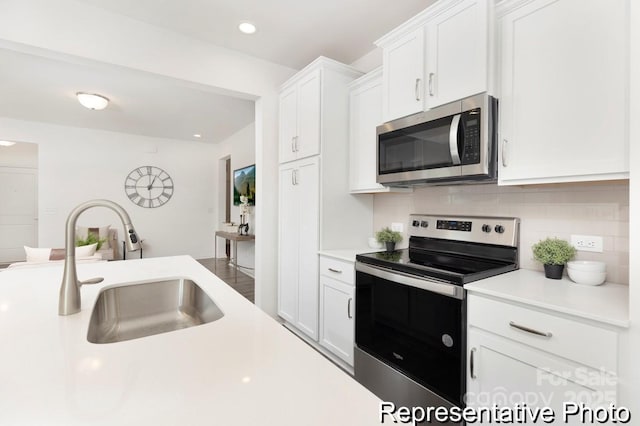 kitchen featuring a sink, white cabinets, light countertops, appliances with stainless steel finishes, and decorative backsplash